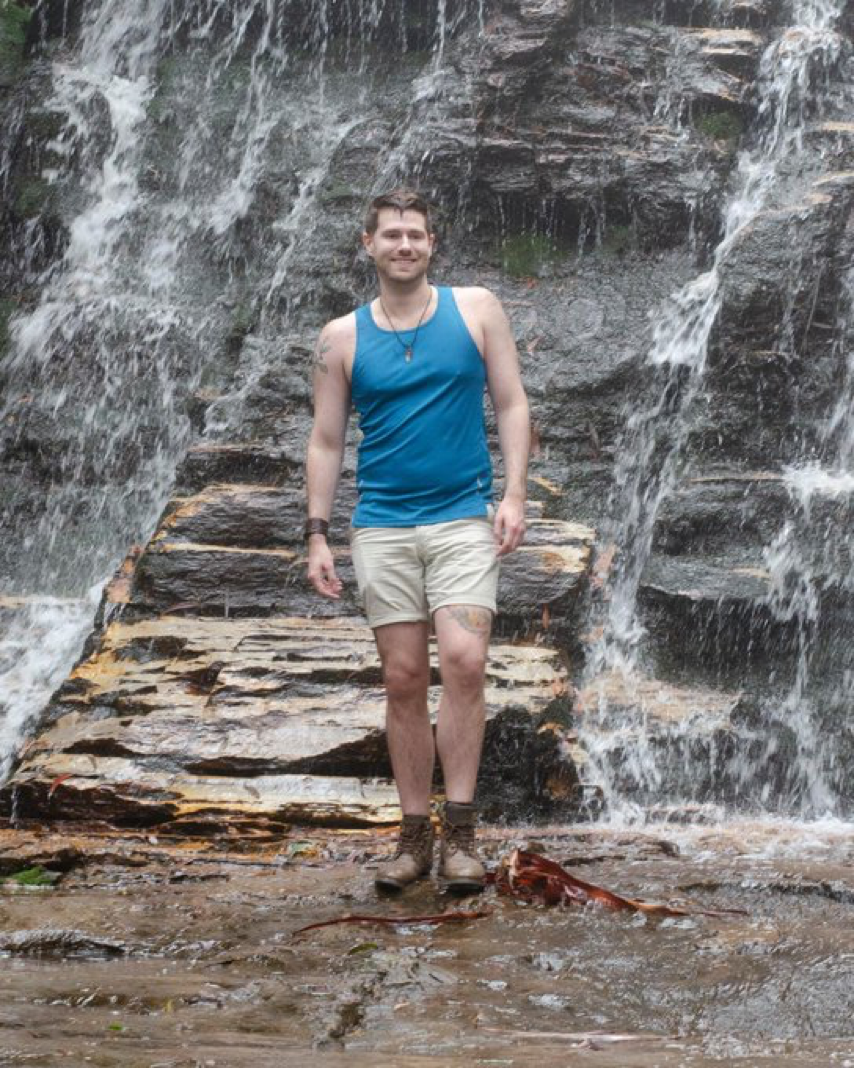 Maxwell standing in front of a waterfall