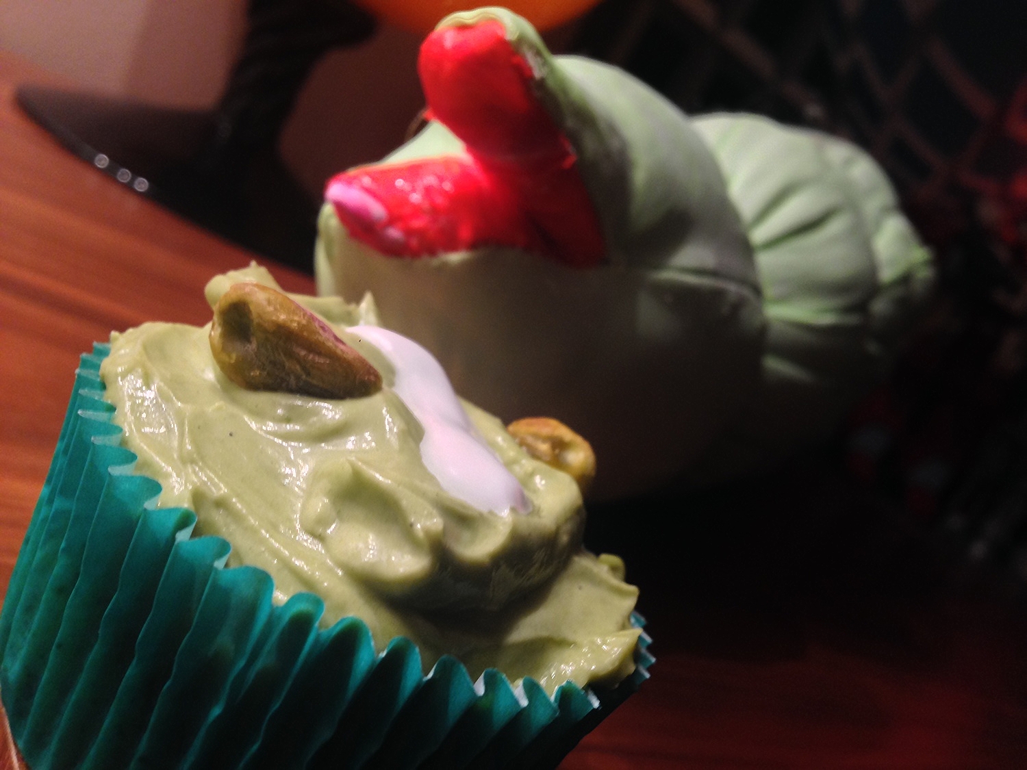 Closeup of a green iced cupcake being menaced by a puppet maggot